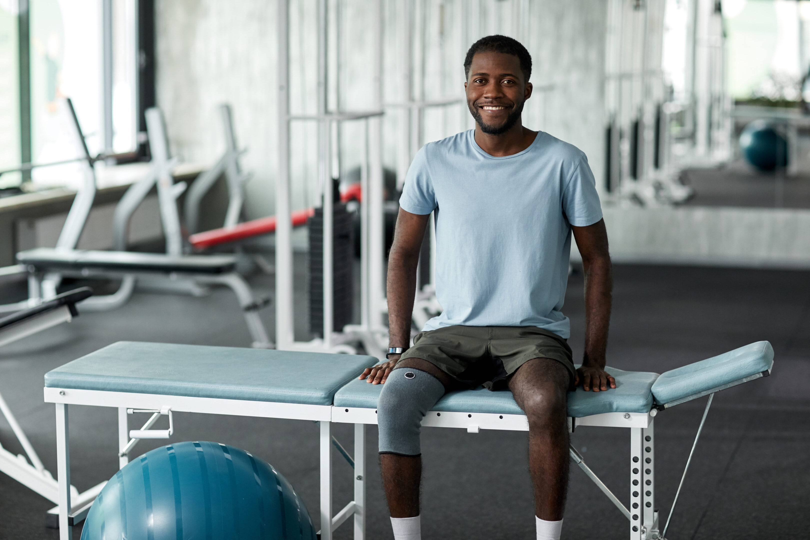 Man sitting on a massage table, smiling.