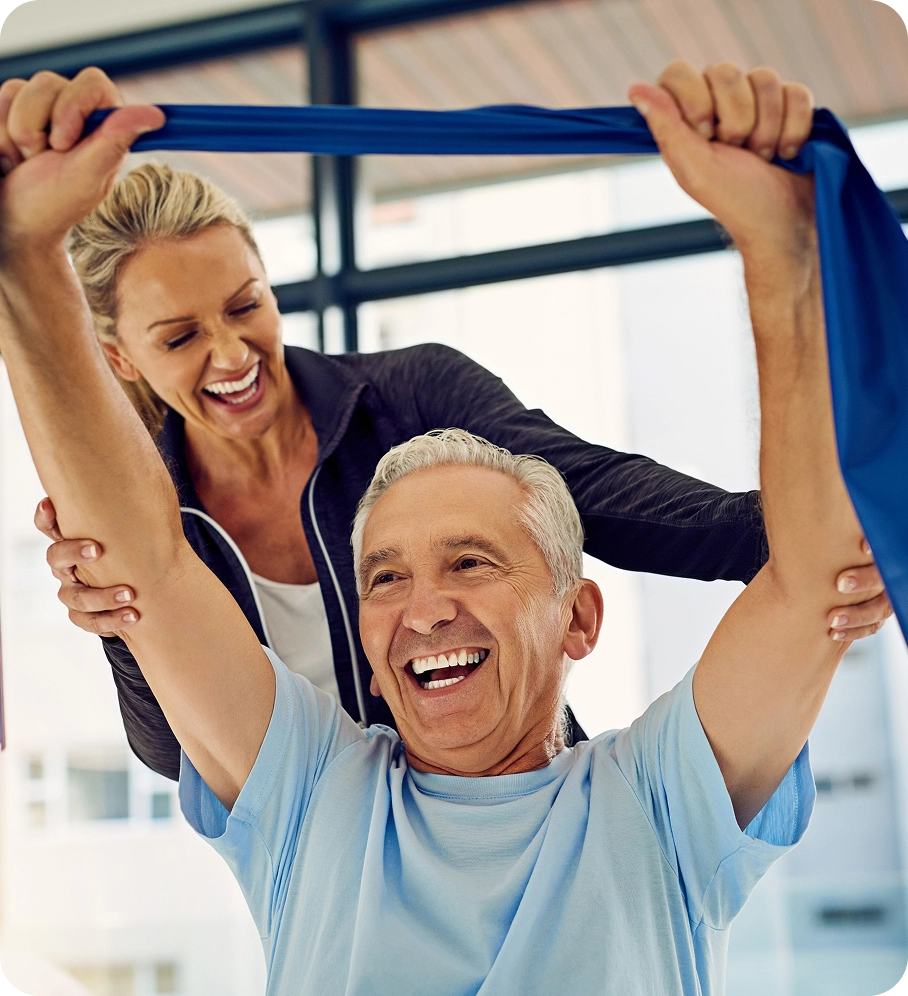 Elderly man exercising with assistance, smiling.