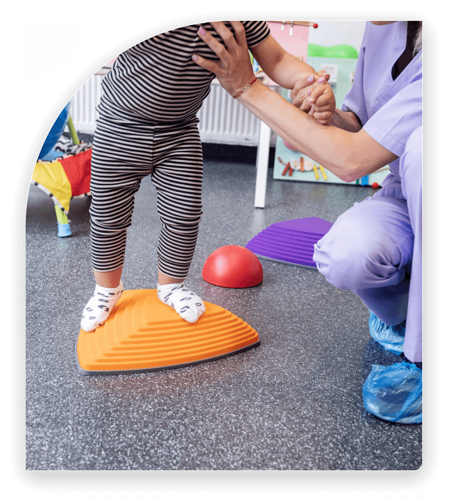 Child balancing on orange wedge, assisted.